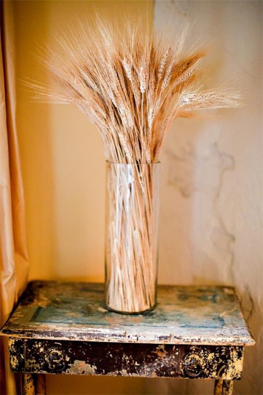 Syksyn koristelu vehnän korkealla lasimaljakoilla vehnänvarret, jotka on järjestetty siihen Vintage -pöytä huoneen nurkassa