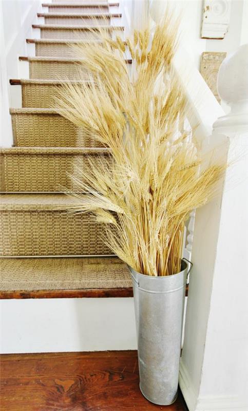 Syksyn koristelu vehnällä luonnon kauneutta Eri pituiset vehnänvarret sinkkipurkissa käytävän portaiden edessä