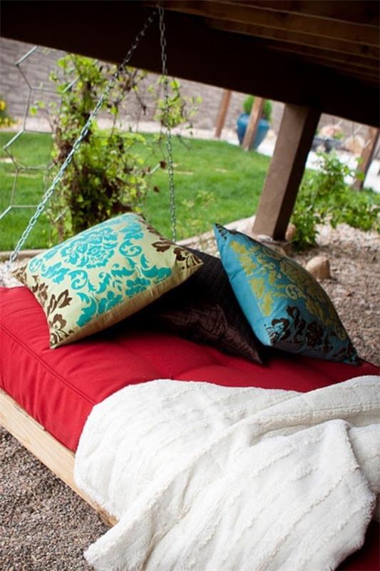 Riippuva sänky ulkona värikkäillä tyynyillä taustalla vihreänä puutarhana