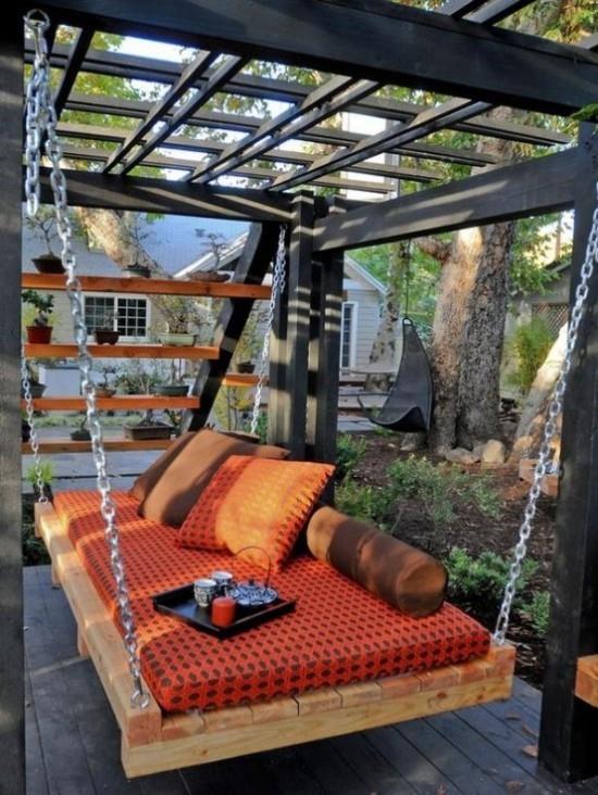 Riippuva sänky ulkona puutarhassa oranssinvärinen verhoilu, tarjotin, jossa on kahvikupin kynttilä
