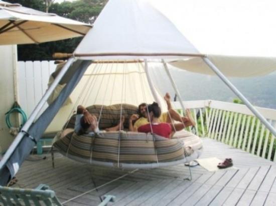 Riippuva sänky modernin mallin ulkopuolella pyöreässä muodossa teltta nuoret huvittavat tuntia