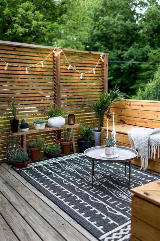 Luo yksinkertaisesti puinen terassi maalaismaiseen, värikkääseen mattoon, keiju valot puuseinään