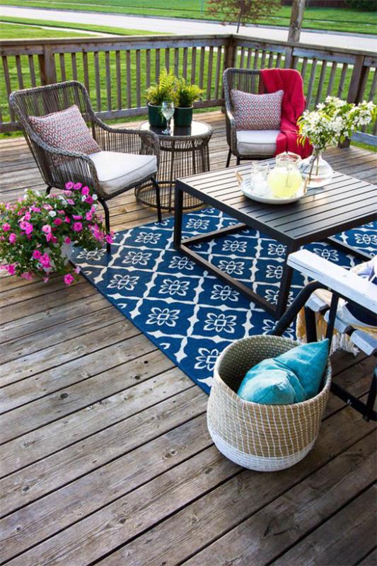 Puinen terassi suunnittelu harmaa puinen lankut sininen matto mukavat huonekalut kasvit kukat