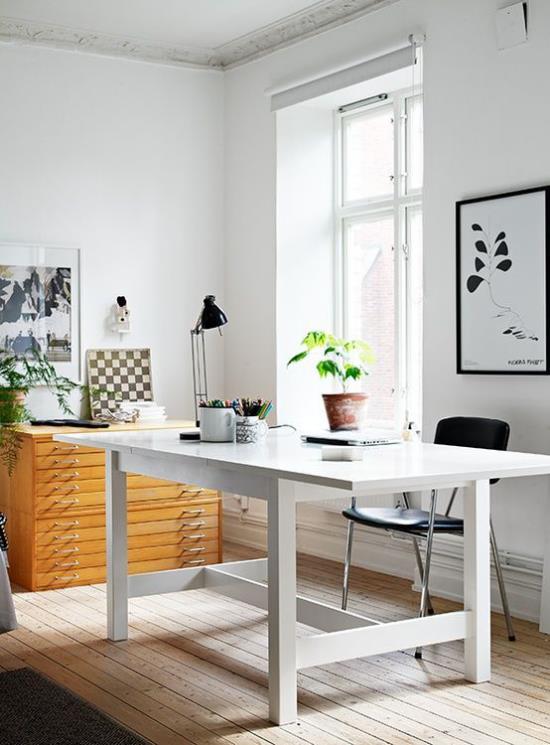 Kotitoimisto neutraaleissa väreissä, paljon päivänvaloa, valkoinen pöytä, pieni musta lamppu