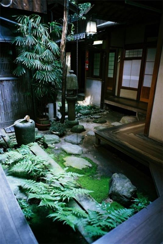 Japanilainen takapihan puutarhan värivalikoima vihreä vesisuihkulähde sammalta kivet saniainen