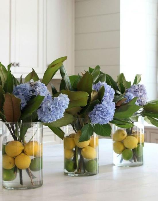 Keittiön kevät koristele sinisiä hortensioita kolmessa lasissa keltaisia ​​sitruunoita vedessä