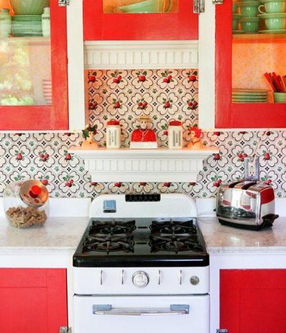 Keittiön takaseinä, jossa on kukkakuviointi ja kauniisti kuvioitu tapetti, virkistää keittiön valkoiseksi ja punaiseksi