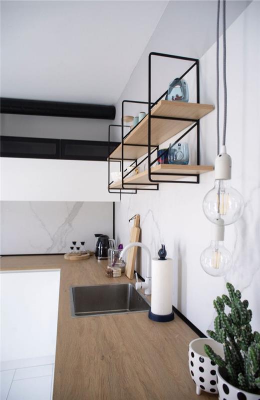 Pieni huoneisto perustettu L -muotoinen keittiö minimalistisesti suunniteltu valkoiset seinät avoin hylly puiset työtasot upottavat kaktuksia kattilaan
