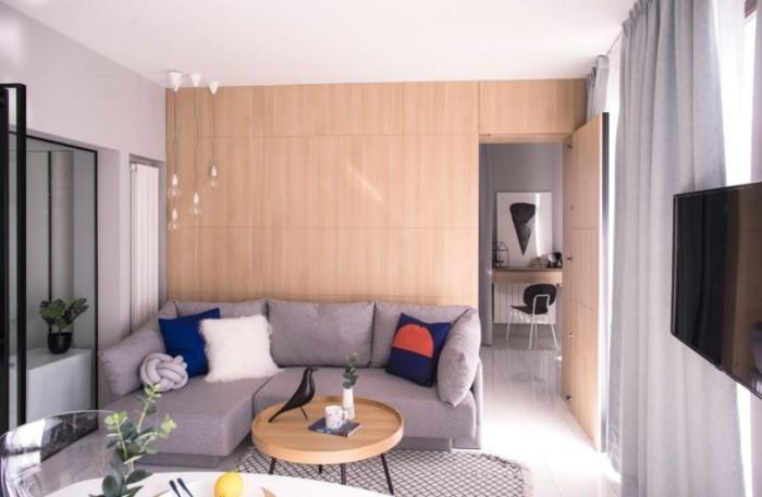 Perusta pieni asunto olohuone harmaa kulmasohva koristetyynyt pieni pyöreä sohvapöytä