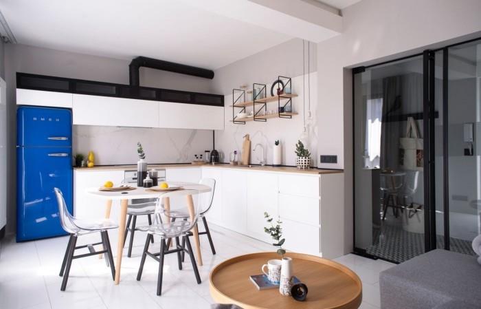 Pieni huoneisto, jossa on rajoitettu asuintila 48 neliömetrin minimalistinen keittiö sininen jääkaappi ruokapöytä muovituolit