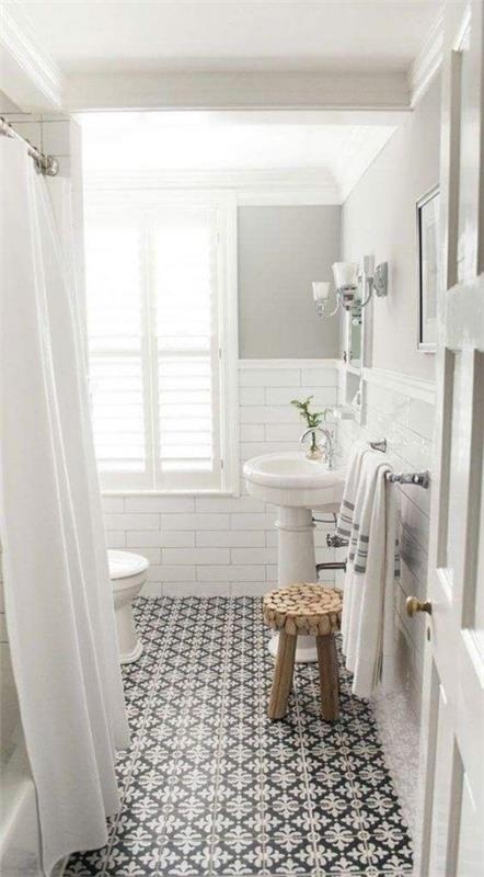 Pieni kylpyhuone, kaikki valkoiset, kauniisti kuvioidut lattialaatat, mustavalkoinen katseenvangitsija
