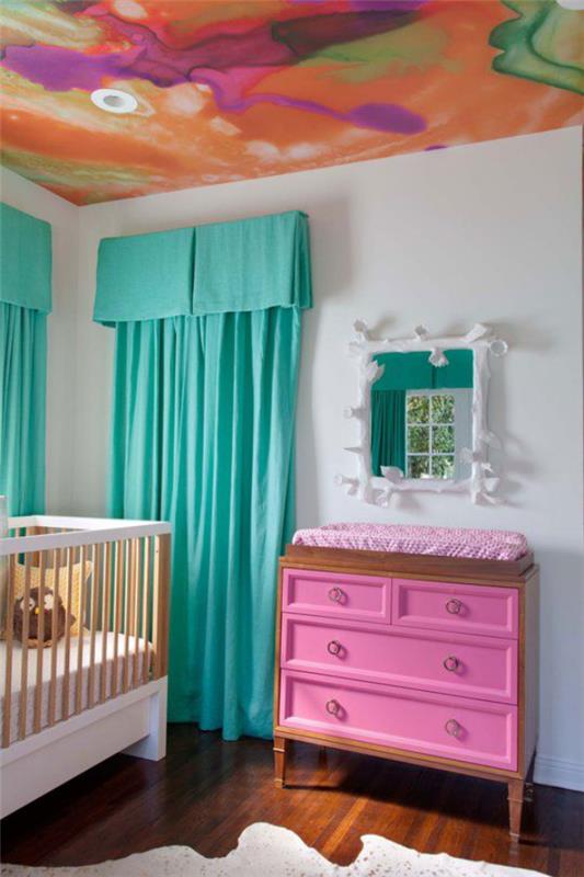 Sekalainen vauvan huone kirkkaasti maalattu katto turkoosi sininen verhot valkoinen sänky vaaleanpunainen hoitopöytä