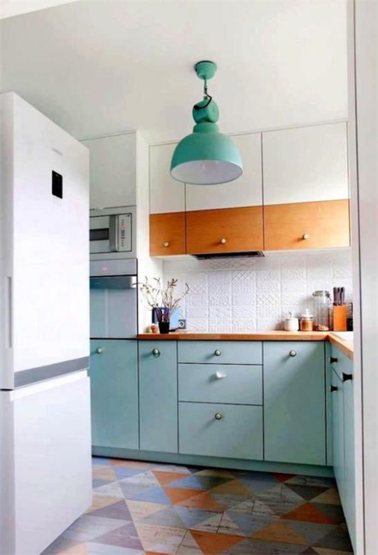 L-keittiön hankala kulma, jossa on ikkunakeittiö, L-muotoisia värikkäitä kolmion muotoisia lattialaattoja, valkoinen jääkaappi