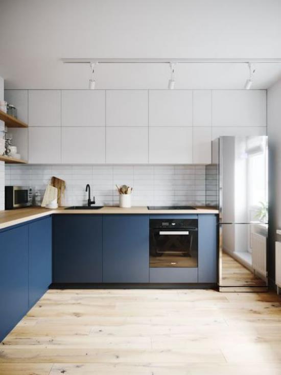 L-keittiön tyylikäs keittiösuunnittelu L-muotoisissa tummansinisissä pohjakaapissa valkoiset seinäkaapit puulattiakattovalaistus