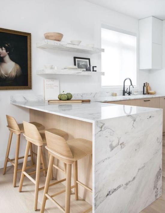 L keittiö valkoinen marmori keittiö saari työtasot vaalea puu hyllyt klassinen maalaus seinälle