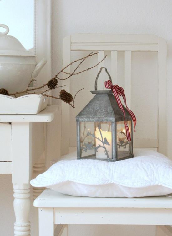 Joululampujen koristelu sisätiloissa ja ulkona vanha sinkkivalaisin valkoinen kynttilä palaa sisällä tuolilla pöydän vieressä