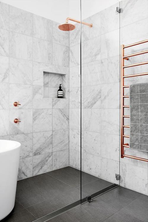 Marmorikylpyhuoneessa marmorilaatat suihkunurkkaus kylpyamme sen vieressä vaaleanharmaa hallitsee messinki aksentteja
