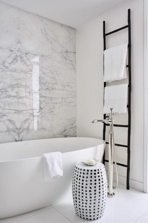 Marmori kylpyhuoneessa marmorilaatat marmoriseinä harmaana kauniina viljana valkoinen kylpyamme raolla mustat tikkaat
