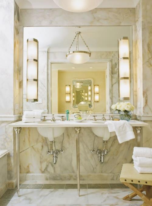 Marmori kylpyhuoneessa marmorilaatat beige mielenkiintoinen vilja iso peili hyvin valaistu.