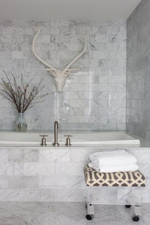 Marmori kylpyhuoneessa marmorilaatat tummanharmaat hirvieläinten sarvet seinällä