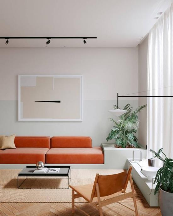 Oranssi sohva tuo lisää väriä sisätiloihin kirkas tunnelma suuri katseenvangitsija vihreät sisäkasvit