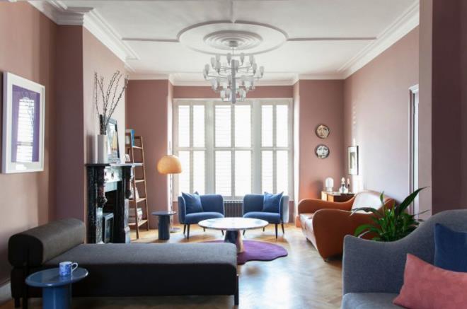 Vuosisadan puolivälin moderni olohuone olohuone vaaleanpunaiset seinät mukavat huonekalut kivitakka violetti matto