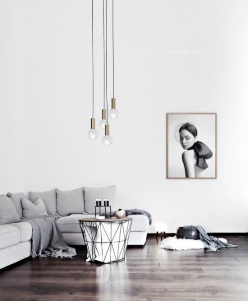 Minimalismi olohuoneen kulmasohvalla pienet pöytäkynttilät riippuvalaisimet seinämaalaus rauhallinen ja yksinkertainen