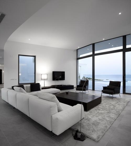 Minimalismi olohuoneessa iso huone kaunis näkymä valkoinen kulmasohva harmaa matto matala pöytä musta
