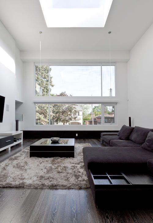 Minimalismi olohuoneessa täydellinen muotoilu tumma kulmasohva matto TV -seinä iso ikkuna paljon luonnonvaloa