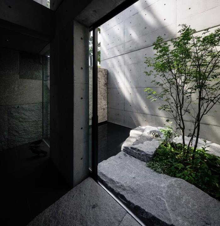 Minimalistinen kivi- ja betonitalo Japanissa sisäpiha mustat laatat luonnonkivi lasiovet luonnollinen valo