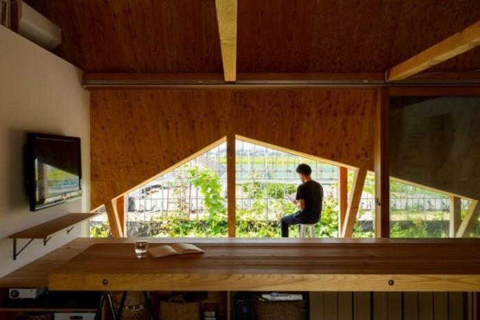 Minimalistinen talo Japanissa, suuret kolmiomaiset ikkunat, joista on näkymät japanilaiseen puutarhaan ja muihin rakennuksiin