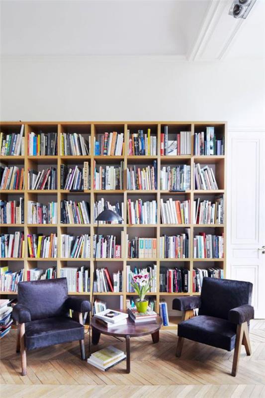 Moderni kotikirjaston lukukulma kaksi nojatuolia pieni pöytä monia kirjoja