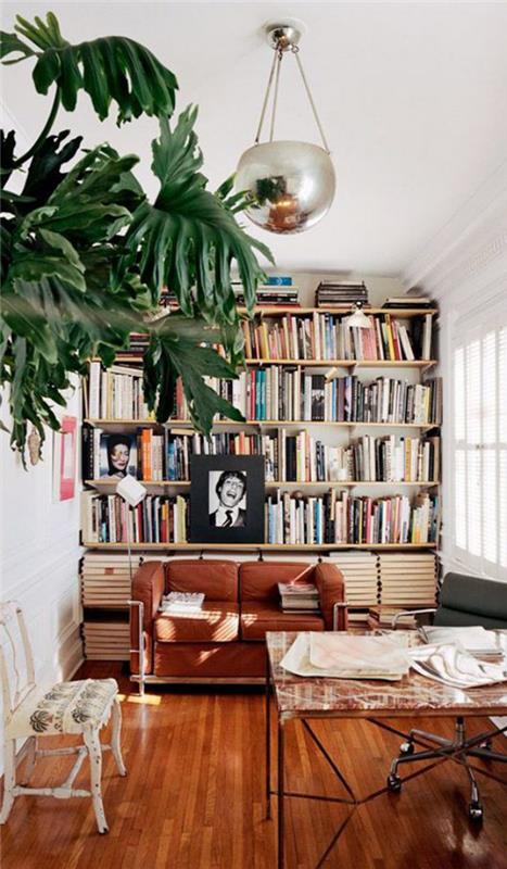Moderni kotikirjaston sohvapöytä pyörillä paljon puuta lämpimiä värejä vihreä huonekasvi