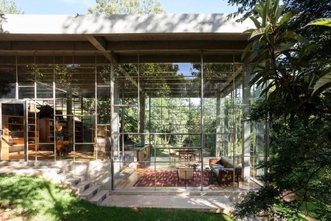 Moderni sademetsään rakennettu lasi- ja betonitalo on harmonisesti integroitu ympäristöön