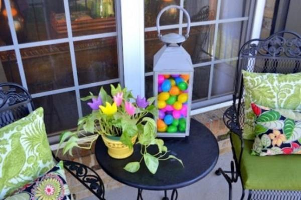 Pääsiäiskoriste ulkoterassilla koristele värikkäitä istuintyynyjä lyhty värikkäillä munilla Kattila, jossa on vihreä kasvi ja kukkia