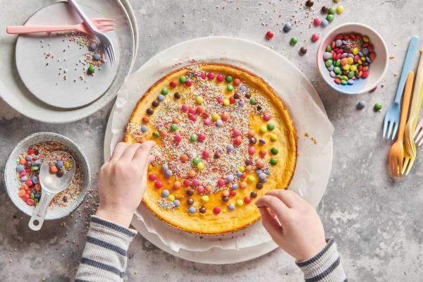 Pääsiäiskakkujen leipominen koristele tomusokerikuorrutus pienillä, värikkäillä suklaamunilla lisäkoristeeksi