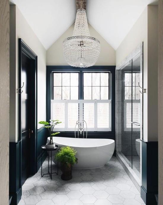 Pariisin tyylikäs kylpyhuoneessa moderni kylpyamme soikea muotoinen tyylikäs huoneen muotoilu kaksi vihreää kasvia korostuksena iso ikkuna kristallikruunu