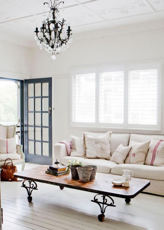 Provence-tyylinen kirkas valoisa olohuone yksinkertaiset huonekalut avoin ovi paljas lattia