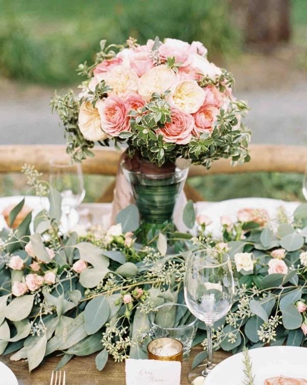 Romanttiset pöytäkoristeet ruusut pehmeillä väreillä vihreät oksat lehdet