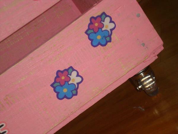 Vaaleanpunainen säilytyslaatikko pyörillä, jotka on valmistettu puulavoista Kinder