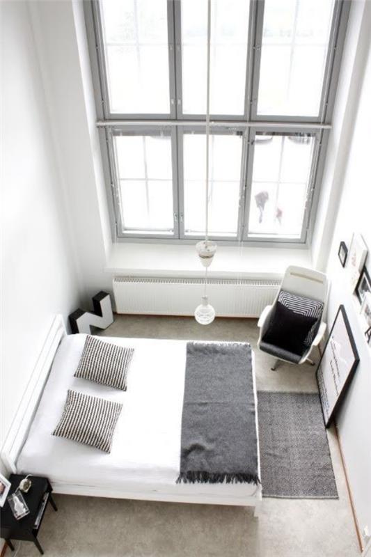 Makuuhuone perustettu minimalistinen suuri ikkuna nukkuva sänky nojatuoli nurkassa vähemmän on enemmän