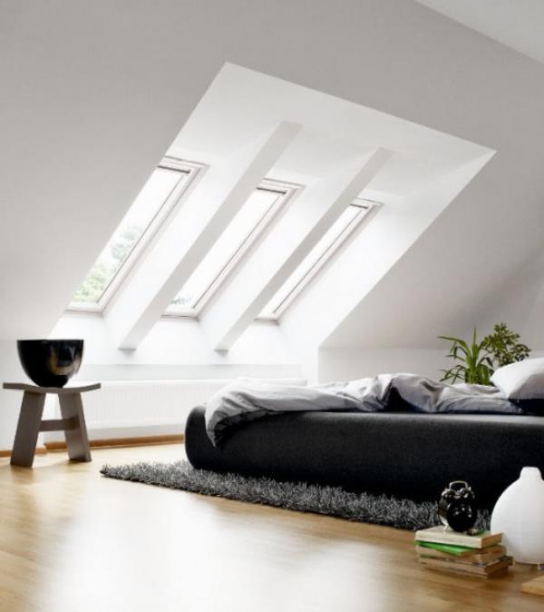 Minimalistinen makuuhuone asetti tyylikkään sisustuksen ullakolle viisto katon kattoikkunan nukkumissängyn alle