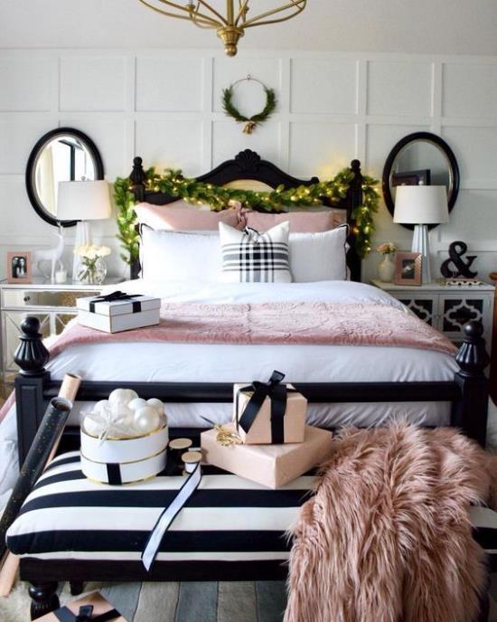 Makuuhuone jouluksi koristaa vaaleanpunaista tekoturkispeitettä vaaleanpunaisella päiväpeitteellä vihreitä seppeleitä