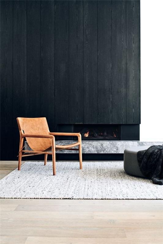 Musta seinä olohuone takka tuoli tummaa taustaa vasten harmaa jakkara matto