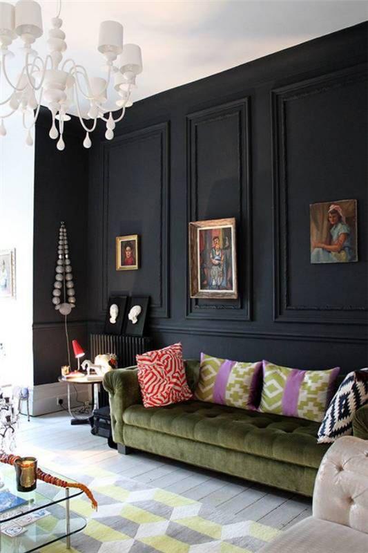 Musta seinä olohuoneessa monia koriste -esineitä kuvia kristallikruunu vihreä nahkasohva värikkäitä tyynyjä