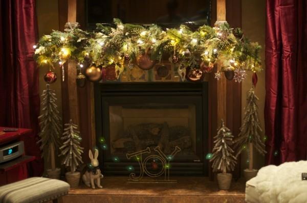 Kotitekoinen takan koristelu kuusen oksilla ja joulupalloilla