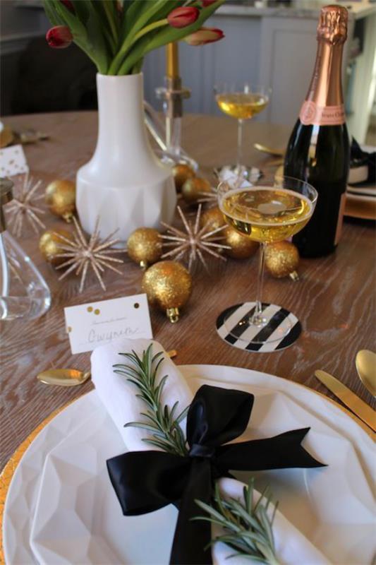 Juhli uudenvuodenaattoa kotona valkoinen lautasliina musta nauha monet kulta glitter samppanjapullo maljakko tulppaaneilla