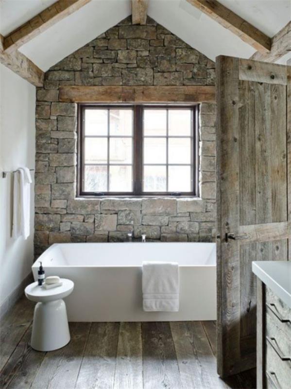 Kivinen kylpyhuone maalaismainen tyyli kiviseinä suorakulmainen ikkuna puuovi moderni kylpyamme jakkara pyyhepidike