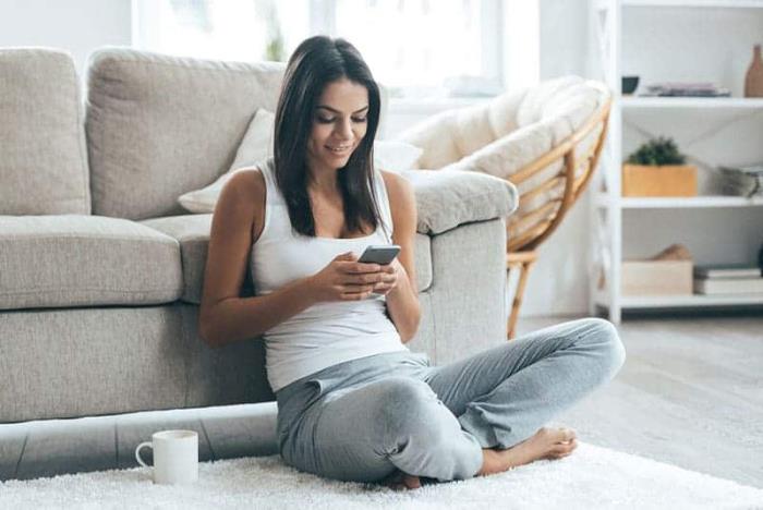 Horoskooppi onnellinen yksin itsenäinen yksinäinen kotona nuori tyttö istuu lattialla kommunikoida matkapuhelimella
