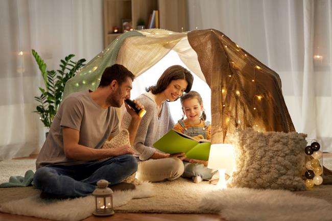 Vältä stressiä koronaviruspandemian aikana kotona, kun lapsi leikkii telttaa ja lukee kirjoja
